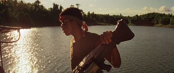 Movie still from “Apocalypse Now” (1979), directed by Francis Ford Coppola – A man holding a gun while standing in a body of water; Medium shot, Low angle