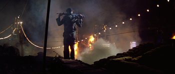 Movie still from “Apocalypse Now” (1979), directed by Francis Ford Coppola – A man holding a gun while standing in front of a fire; Wide shot, Low angle