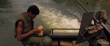 Movie still from “Apocalypse Now” (1979), directed by Francis Ford Coppola – A man sitting on a boat in the water; Medium shot, High angle