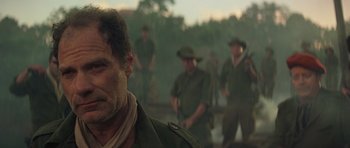 Movie still from “Apocalypse Now” (1979), directed by Francis Ford Coppola – A group of men standing next to each other in a field; Close Up shot, Over the shoulder angle