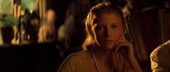 Movie still from “Apocalypse Now” (1979), directed by Francis Ford Coppola – A woman with a pearl necklace is posing for a picture; Close Up shot, Over the shoulder angle