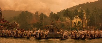Movie still from “Apocalypse Now” (1979), directed by Francis Ford Coppola – A group of people on boats in a body of water with palm trees in the background; Extreme Wide shot, High angle