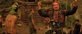 Movie still from “Apocalypse Now” (1979), directed by Francis Ford Coppola – A man with a camera in his hand and a man with a camera in his other hand; Medium shot, Low angle