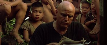 Movie still from “Apocalypse Now” (1979), directed by Francis Ford Coppola – A man with a bald head is reading a book; Close Up shot, Low angle