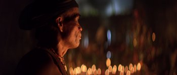 Movie still from “Apocalypse Now” (1979), directed by Francis Ford Coppola – A man standing in front of a group of candles; Close Up shot, Low angle