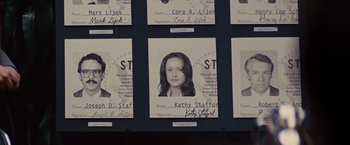 Movie still from “Argo” (2012), directed by Ben Affleck – A group of people are hanging up their id's on the wall; Extreme Close Up shot, Overhead angle