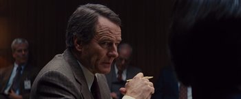 Movie still from “Argo” (2012), directed by Ben Affleck – An older man wearing a suit and tie holding a pencil; Close Up shot, Over the shoulder angle