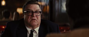 Movie still from “Argo” (2012), directed by Ben Affleck – An older man wearing a suit and glasses; Close Up shot, Over the shoulder angle