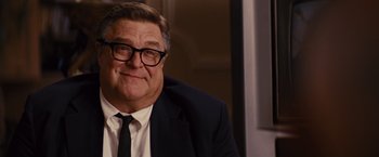 Movie still from “Argo” (2012), directed by Ben Affleck – A person wearing a suit and glasses; Close Up shot, Over the shoulder angle