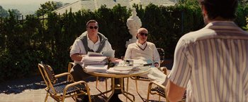 Movie still from “Argo” (2012), directed by Ben Affleck – A couple of men sitting at a table with papers; Medium shot, Over the shoulder angle