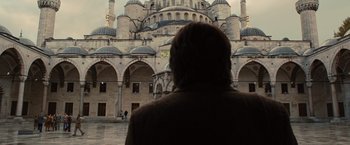 Movie still from “Argo” (2012), directed by Ben Affleck – A person standing in front of a large building; Wide shot, Low angle