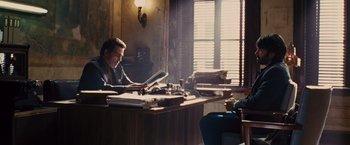 Movie still from “Argo” (2012), directed by Ben Affleck – A man sitting at a desk in front of a window; Wide shot, Over the shoulder angle