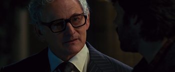 Movie still from “Argo” (2012), directed by Ben Affleck – An older man wearing a suit and glasses; Close Up shot, Over the shoulder angle