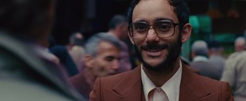 Movie still from “Argo” (2012), directed by Ben Affleck – A person wearing a suit and glasses; Close Up shot, Over the shoulder angle