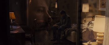 Movie still from “Argo” (2012), directed by Ben Affleck – A man sitting on a bed looking at a phone; Medium shot, Overhead angle