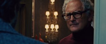 Movie still from “Argo” (2012), directed by Ben Affleck – An older man wearing glasses in front of chandeliers; Close Up shot, Over the shoulder angle
