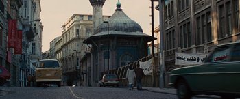 Movie still from “Argo” (2012), directed by Ben Affleck – Two people walking down a street in front of a building; Extreme Wide shot, Low angle