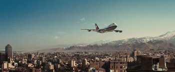 Movie still from “Argo” (2012), directed by Ben Affleck – An airplane is flying over a city with mountains in the background; Extreme Wide shot, Low angle