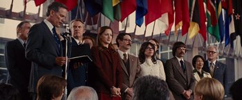 Movie still from “Argo” (2012), directed by Ben Affleck – A group of people standing next to each other in front of flags; Medium shot, Low angle