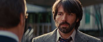 Movie still from “Argo” (2012), directed by Ben Affleck – A man in a suit and tie looking at the camera; Close Up shot, Over the shoulder angle