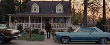Movie still from “Argo” (2012), directed by Ben Affleck – A man standing in front of a house next to a car; Wide shot, Over the shoulder angle