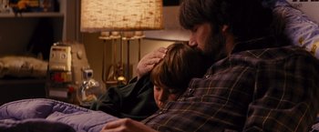Movie still from “Argo” (2012), directed by Ben Affleck – A man and a boy sitting on a couch together; Medium shot, Overhead angle