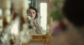 Movie still from “Atonement” (2007), directed by Joe Wright – A woman is looking into a mirror holding a flower; Close Up shot, Over the shoulder angle