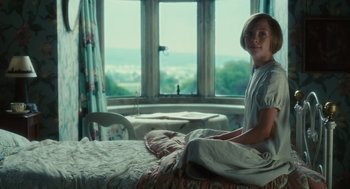 Movie still from “Atonement” (2007), directed by Joe Wright – A woman sitting on a bed in front of a window; Medium shot, Low angle