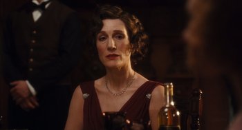 Movie still from “Atonement” (2007), directed by Joe Wright – An older woman wearing a red dress with a wine bottle in front of her; Close Up shot, Over the shoulder angle