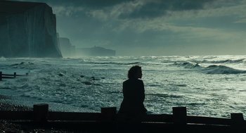 Movie still from “Atonement” (2007), directed by Joe Wright – A woman sitting on a ledge looking out at the ocean; Extreme Wide shot, Low angle