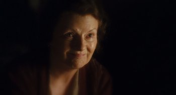 Movie still from “Atonement” (2007), directed by Joe Wright – An older woman is smiling for the camera in the dark; Close Up shot, High angle