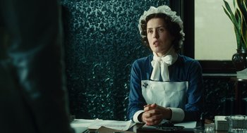 Movie still from “Atonement” (2007), directed by Joe Wright – A woman sitting at a table in a room; Medium shot, Low angle
