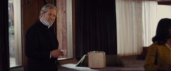 Movie still from “Bad Times at the El Royale” (2018), directed by Drew Goddard – An older man standing next to an open suitcase; Medium shot, Over the shoulder angle