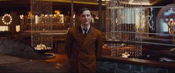Movie still from “Bad Times at the El Royale” (2018), directed by Drew Goddard – A man in a brown suit standing in front of a fountain; Medium shot, Low angle