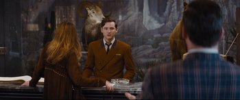 Movie still from “Bad Times at the El Royale” (2018), directed by Drew Goddard – A man in a brown suit is standing in front of a mirror; Medium shot, Over the shoulder angle