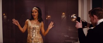 Movie still from “Bad Times at the El Royale” (2018), directed by Drew Goddard – A woman in a gold dress singing into a microphone; Medium shot, High angle