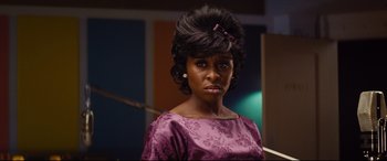 Movie still from “Bad Times at the El Royale” (2018), directed by Drew Goddard – A woman in a purple dress with a pink bow in her hair; Close Up shot, Over the shoulder angle