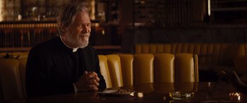 Movie still from “Bad Times at the El Royale” (2018), directed by Drew Goddard – An older man sitting at a table in front of a plate of food; Medium shot, Over the shoulder angle