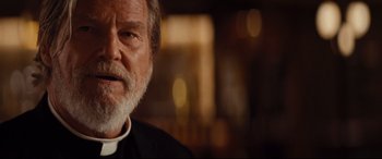 Movie still from “Bad Times at the El Royale” (2018), directed by Drew Goddard – An older man wearing a priest's outfit; Close Up shot, Over the shoulder angle