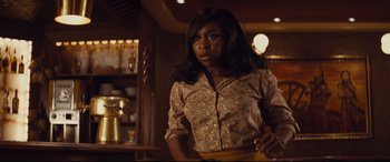 Movie still from “Bad Times at the El Royale” (2018), directed by Drew Goddard – A woman standing in front of a counter; Medium shot, Over the shoulder angle