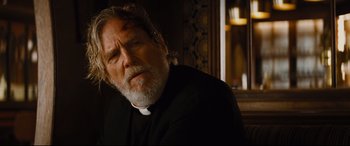 Movie still from “Bad Times at the El Royale” (2018), directed by Drew Goddard – An older man in a priest's outfit looking at the camera; Close Up shot, Over the shoulder angle