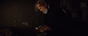 Movie still from “Bad Times at the El Royale” (2018), directed by Drew Goddard – An older man looking at something in a tin can; Medium shot, Low angle