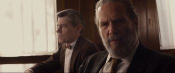 Movie still from “Bad Times at the El Royale” (2018), directed by Drew Goddard – Two older men in suits and ties sitting next to each other in front of a window; Close Up shot, Over the shoulder angle