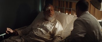 Movie still from “Bad Times at the El Royale” (2018), directed by Drew Goddard – An old man in a hospital bed with bandages on his head; Medium shot, High angle