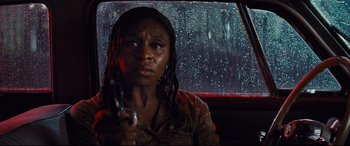 Movie still from “Bad Times at the El Royale” (2018), directed by Drew Goddard – A woman sitting in a car holding a gun in her hand; Close Up shot, Low angle
