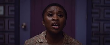 Movie still from “Bad Times at the El Royale” (2018), directed by Drew Goddard – A woman with short black hair wearing a brown shirt; Close Up shot, Low angle