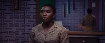 Movie still from “Bad Times at the El Royale” (2018), directed by Drew Goddard – A woman standing in front of a brick wall; Close Up shot, High angle