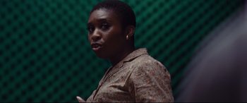 Movie still from “Bad Times at the El Royale” (2018), directed by Drew Goddard – A woman standing in front of a green wall; Close Up shot, High angle