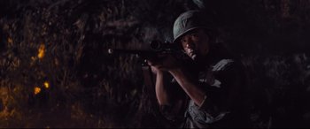 Movie still from “Bad Times at the El Royale” (2018), directed by Drew Goddard – A man with a rifle in a dark forest; Medium shot, High angle