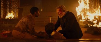 Movie still from “Bad Times at the El Royale” (2018), directed by Drew Goddard – Two men sitting on the ground in front of a statue; Medium shot, Low angle